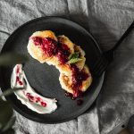 Tasty pancakes topped with fresh berry sauce on a ceramic plate, perfect for a gourmet breakfast.